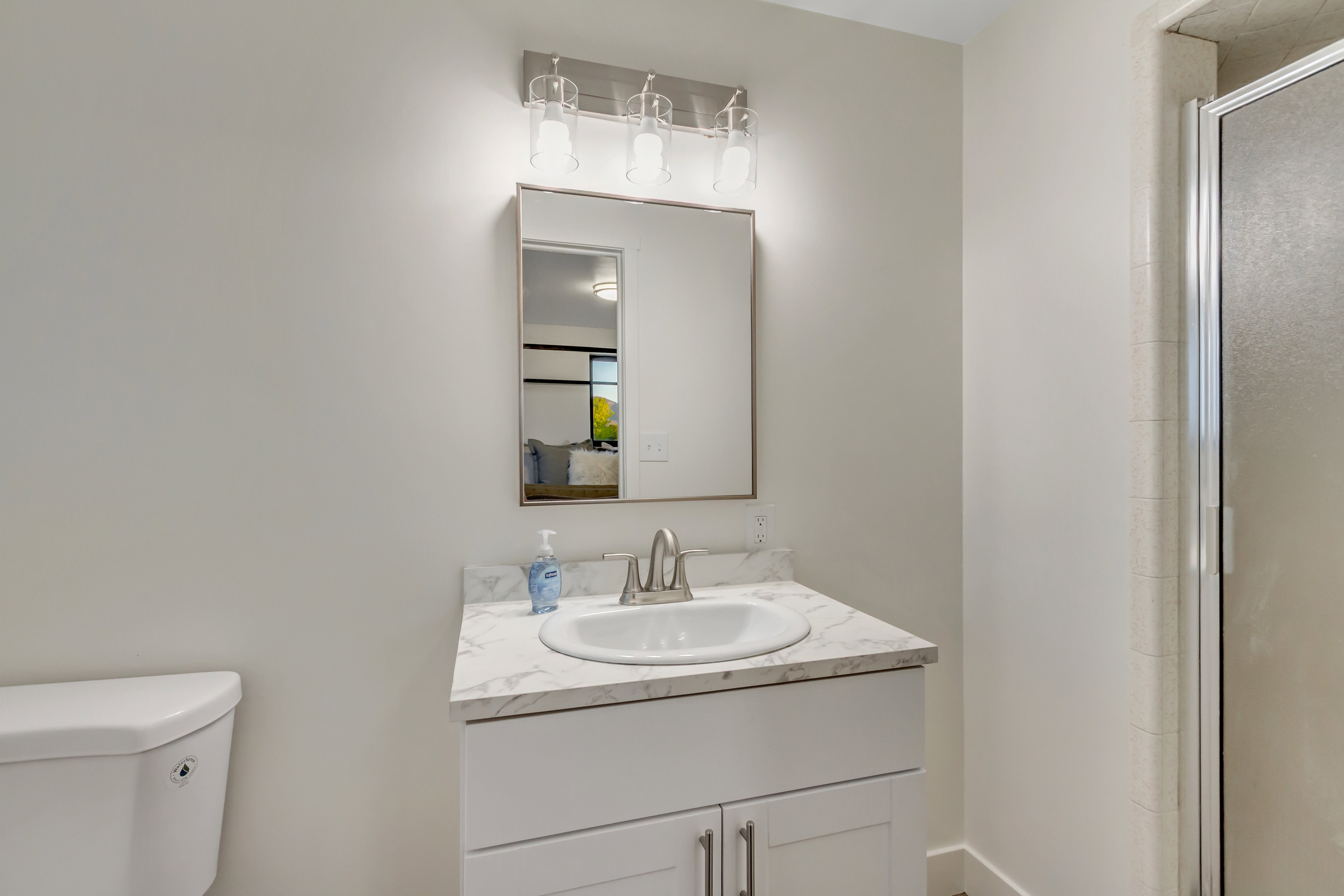 Bathroom vanity with a white integrated sink, polished chrome faucet, and a stone-look countertop