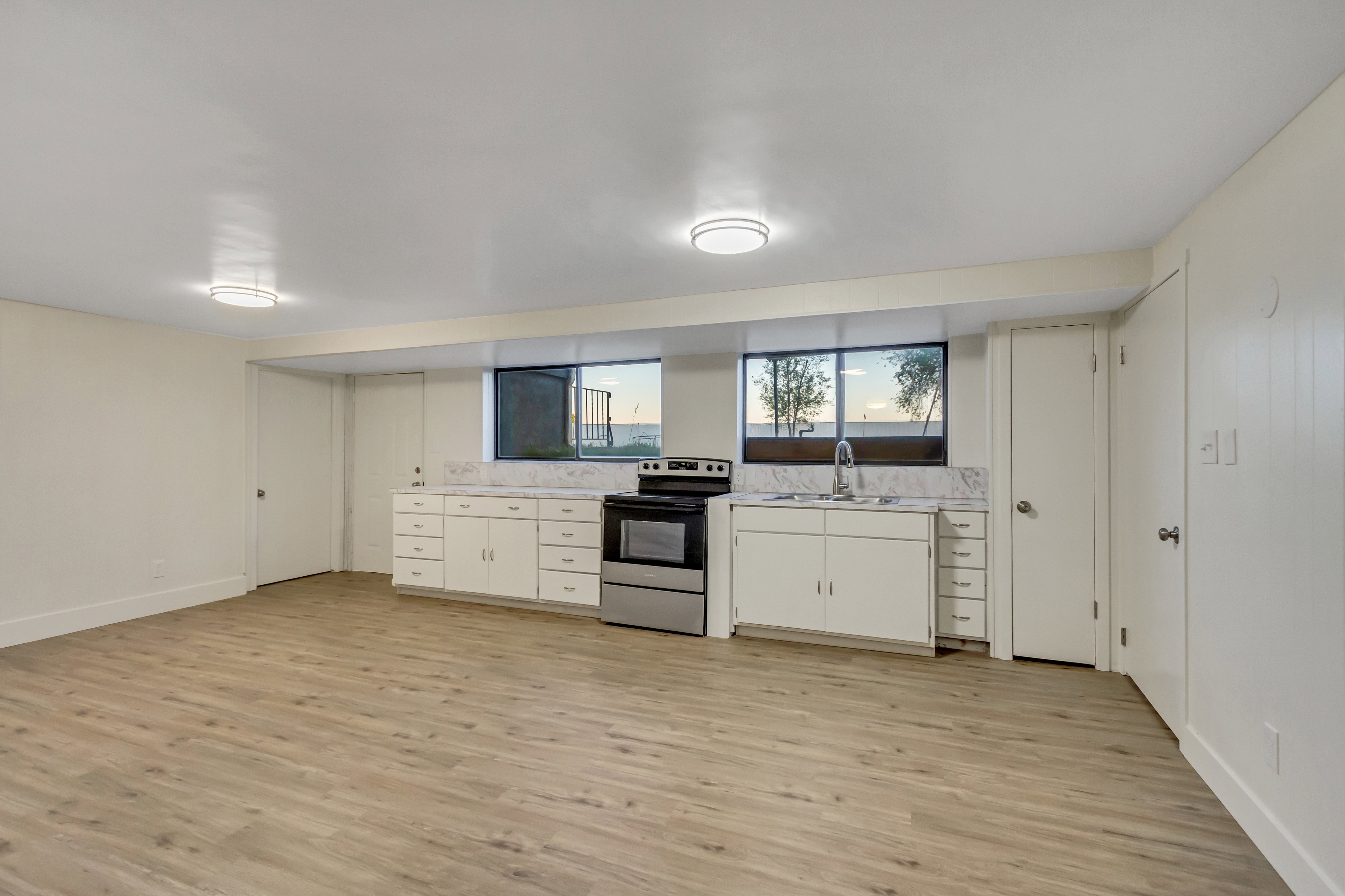 Kitchenette featuring white cabinetry, a stainless steel range, and a stainless steel sink with a window above
