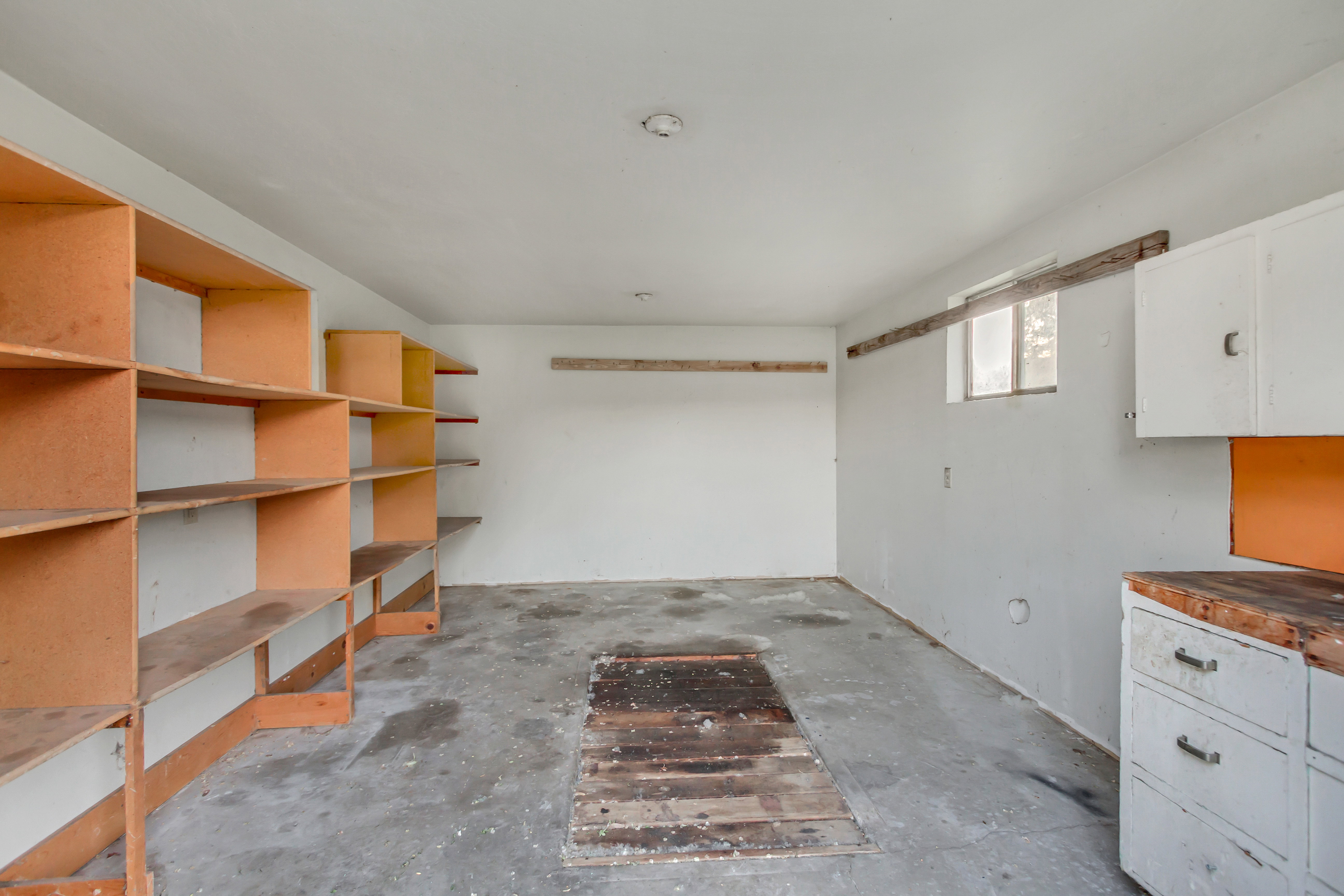 Utility room with concrete flooring, built-in shelving, and a small window