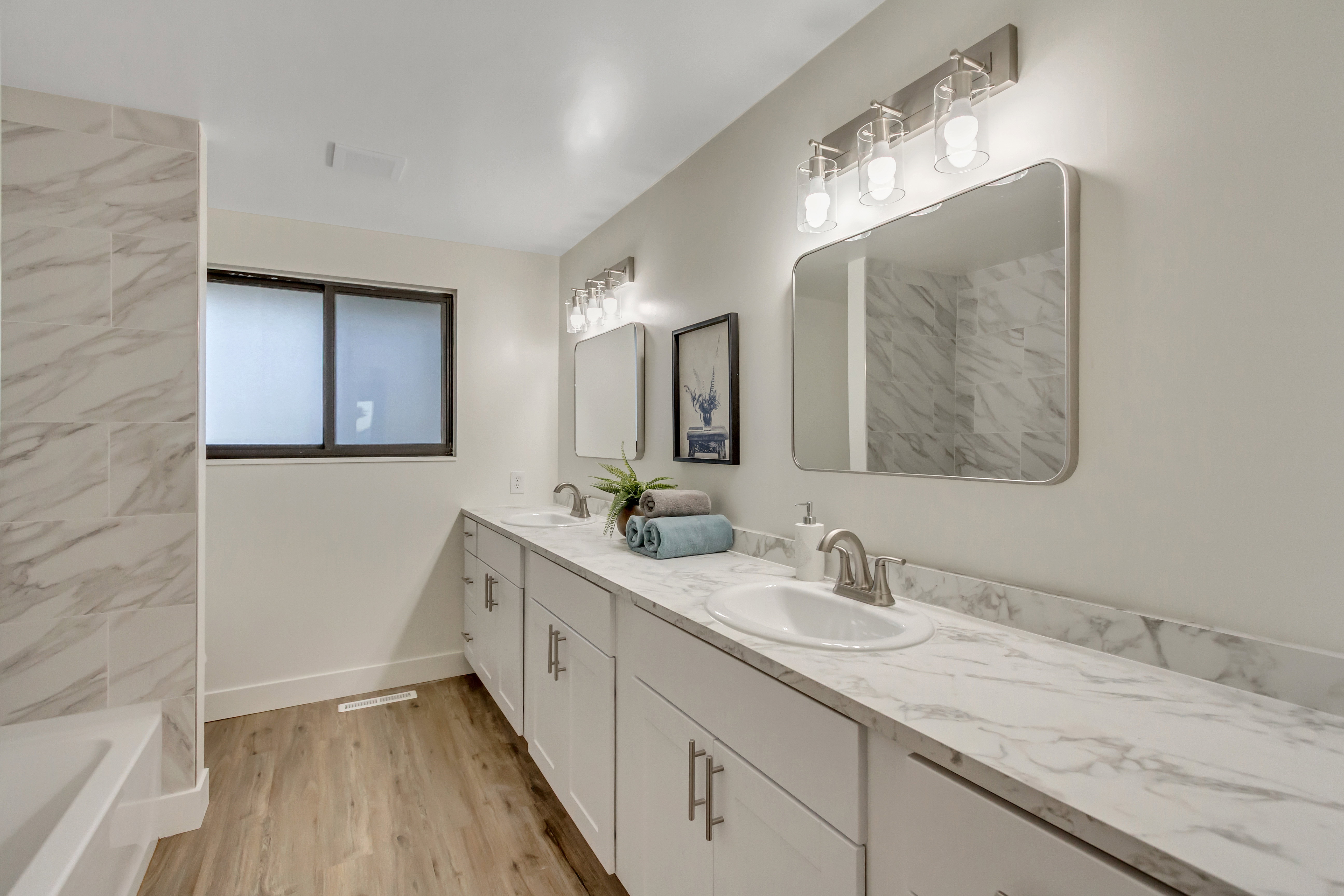 Dual vanity featuring white cabinetry, undermount sinks, and marble-finish countertops