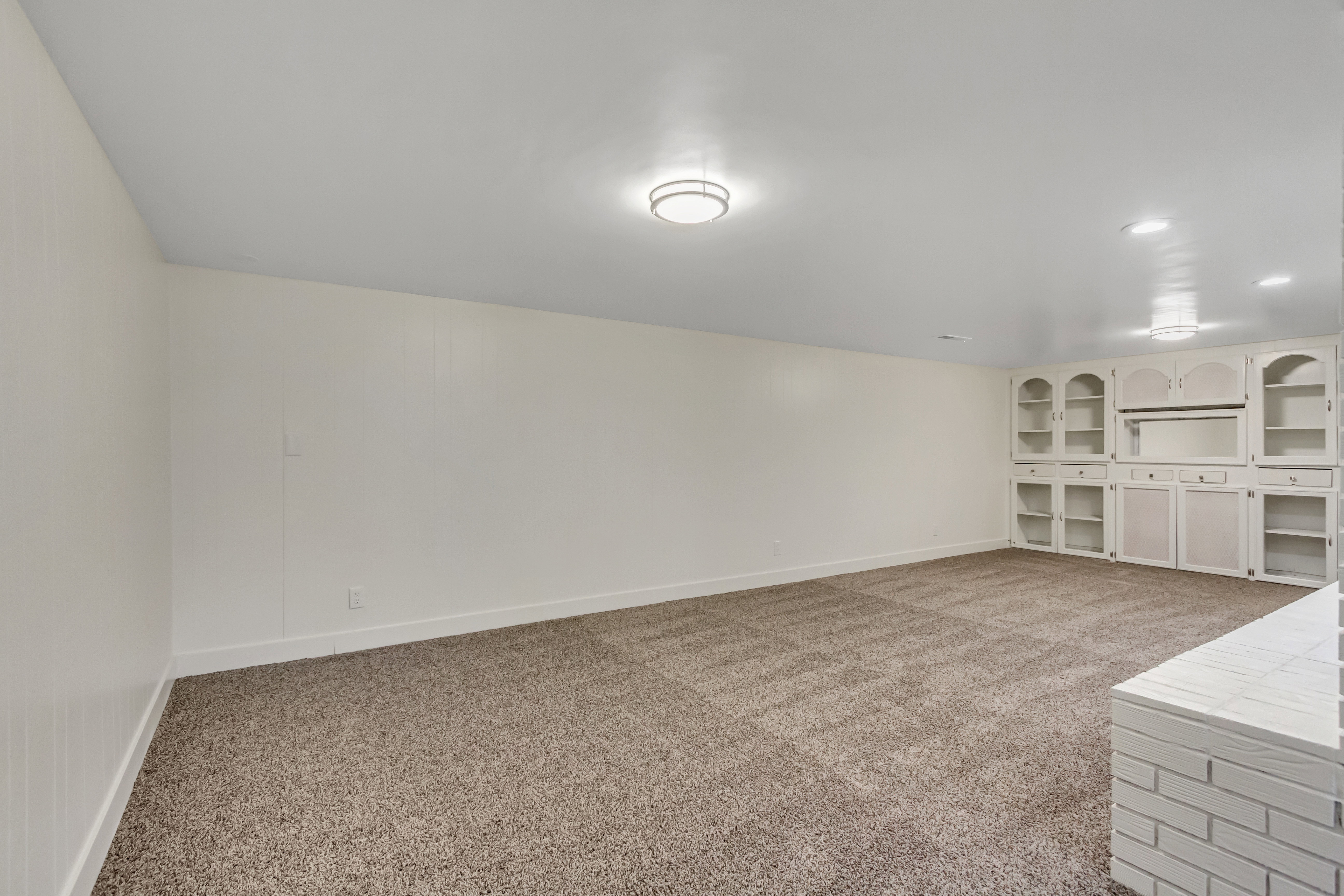 Spacious room featuring neutral carpet flooring and white walls