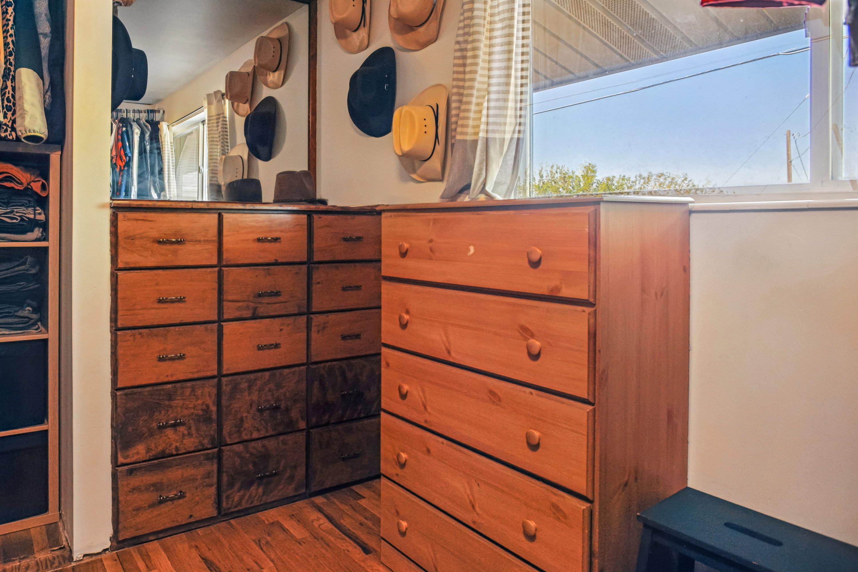 Built-in wood cabinetry with multiple drawers, a full-height mirror, and a window providing natural light