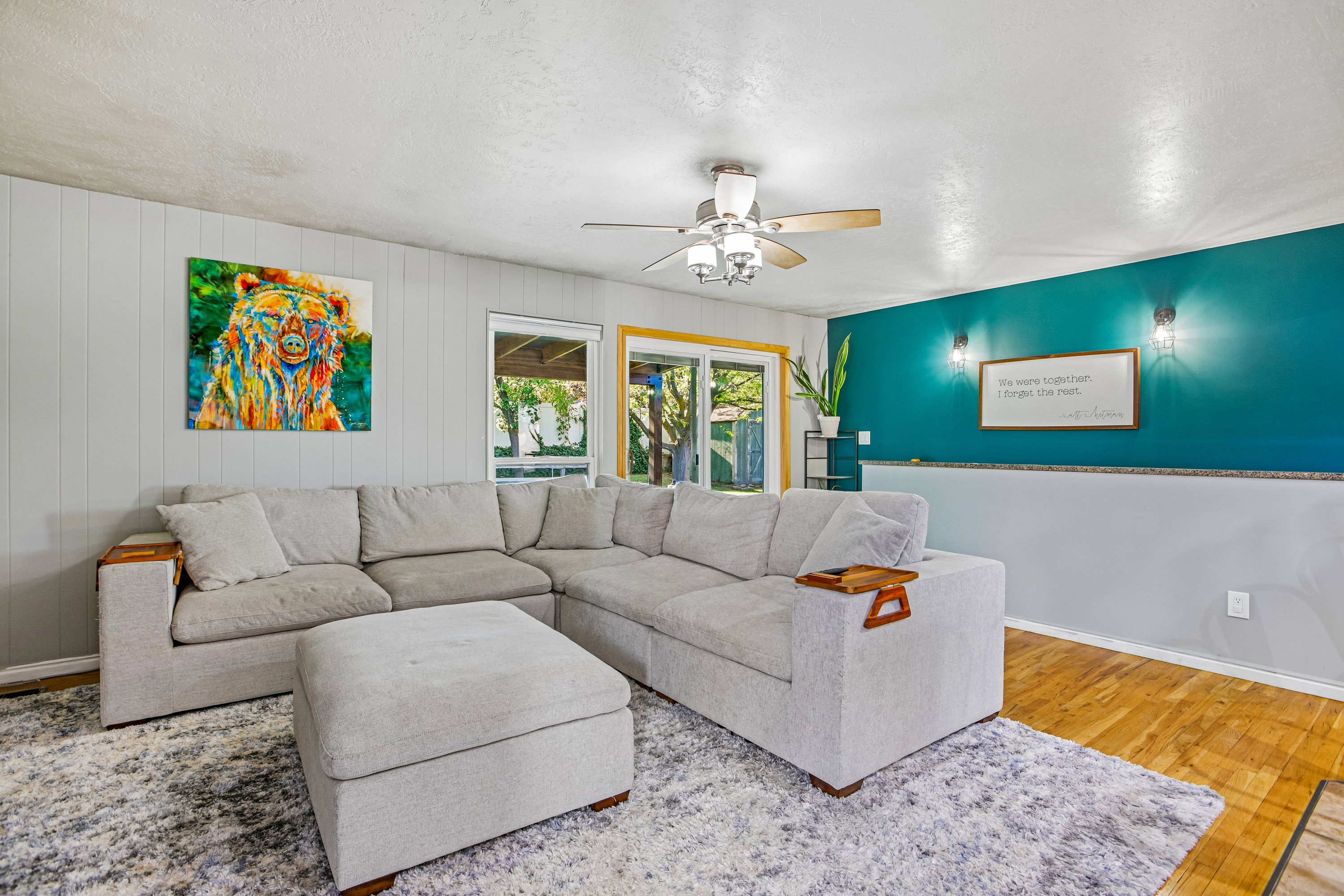Bright interior with wood-finish flooring, a ceiling fan, and paneling on the walls