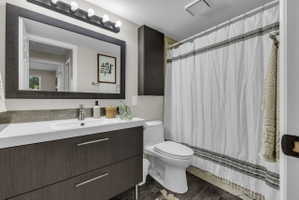 Secondary Bathroom featuring deep soaker tub, dark wood-finish vanity with dual drawers, a white integrated sink