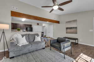 Living area featuring wood-finish flooring, vaulted ceilings, and a ceiling fan