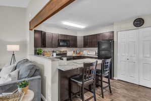Kitchen featuring dark wood-finish cabinetry, light-toned countertops, tile backsplash, and stainless steel appliances