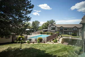 Manicured grounds featuring a swimming pool, fenced perimeter, and established landscaping