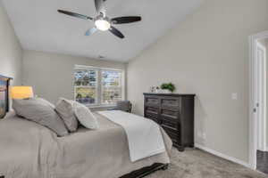 Bedroom featuring a vaulted ceiling, a ceiling fan with integrated lighting, and carpet flooring