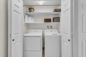 Dedicated laundry closet with white panel doors, overhead shelving, and a built-in overhead light fixture