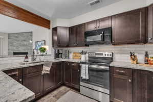 Kitchen featuring dark wood-finish cabinetry, light-toned countertops, a stainless steel electric range, a built-in microwave, and subway tile backsplash