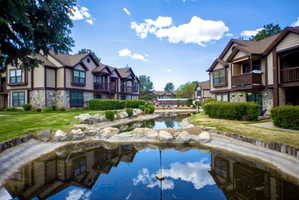 Community buildings featuring stone and siding exteriors, private balconies, and surrounding green spaces