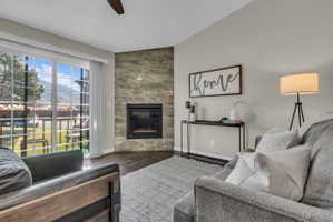 Living area featuring a corner fireplace with a textured stone surround, dark wood-finish flooring, and light wall paint