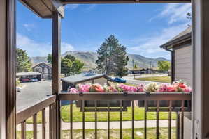 Outdoor balcony with a flower box featuring pink and white blooms, overlooking a mountain range