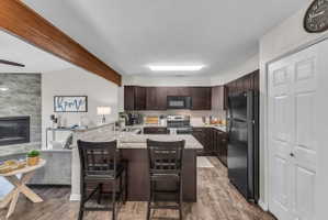 Kitchen with wood-finish flooring, dark wood cabinetry, and light-toned countertops