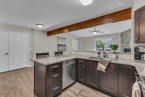 Open-concept kitchen with dark wood-finish cabinetry, light-toned countertops, and a subway tile backsplash