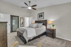 Bright bedroom featuring a vaulted ceiling with a ceiling fan, a sliding barn door with frosted glass, and a door leading to another room