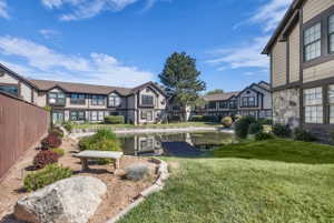 Community pond with a small dock, surrounded by manicured landscaping and mature trees