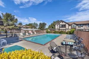 Community swimming pool with a concrete deck and dark brown privacy fencing