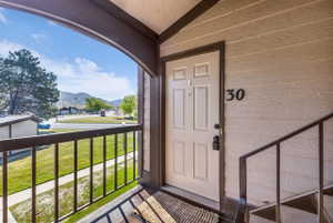 Private balcony entry featuring a beige paneled door, dark brown trim, and metal railings