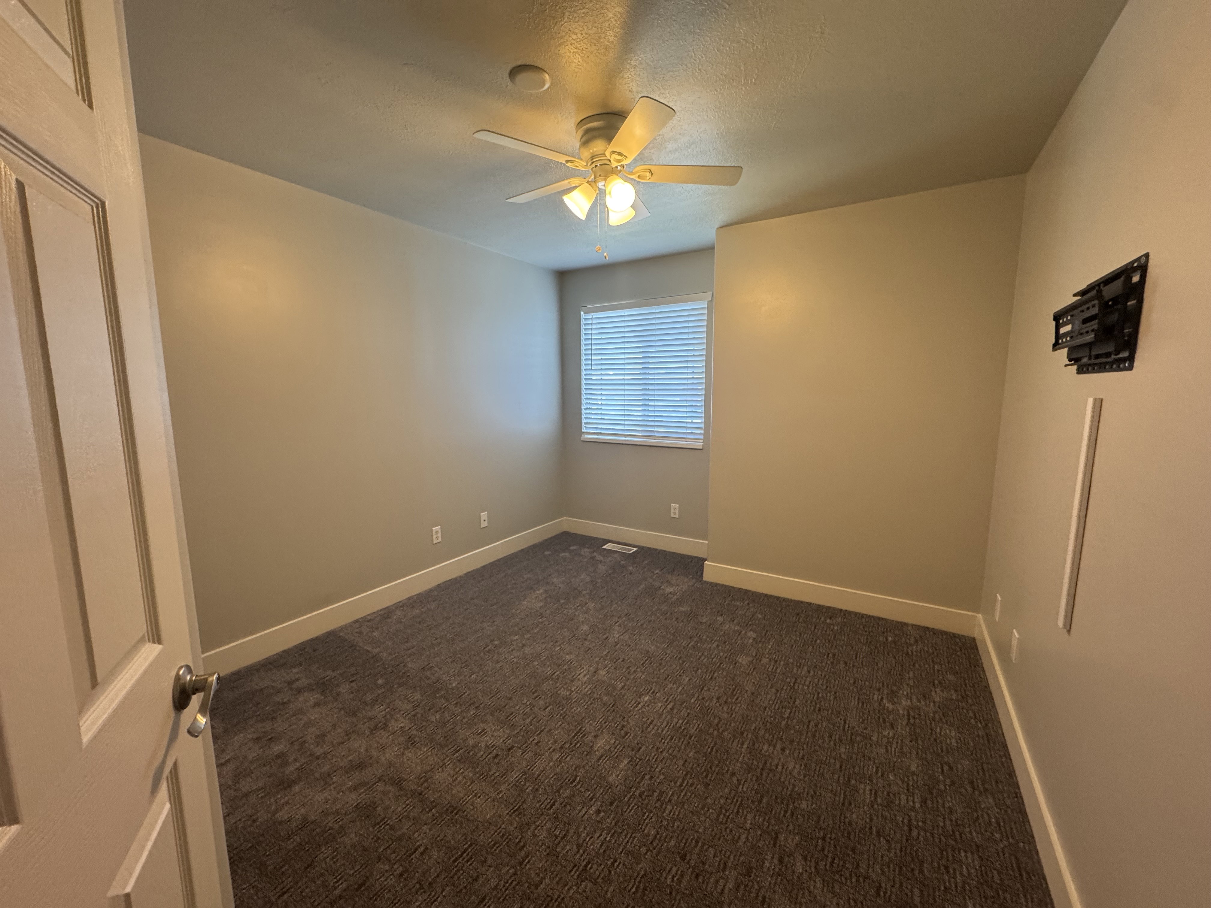 Carpeted room featuring a ceiling fan with integrated lighting, a window with horizontal blinds, and neutral-toned walls