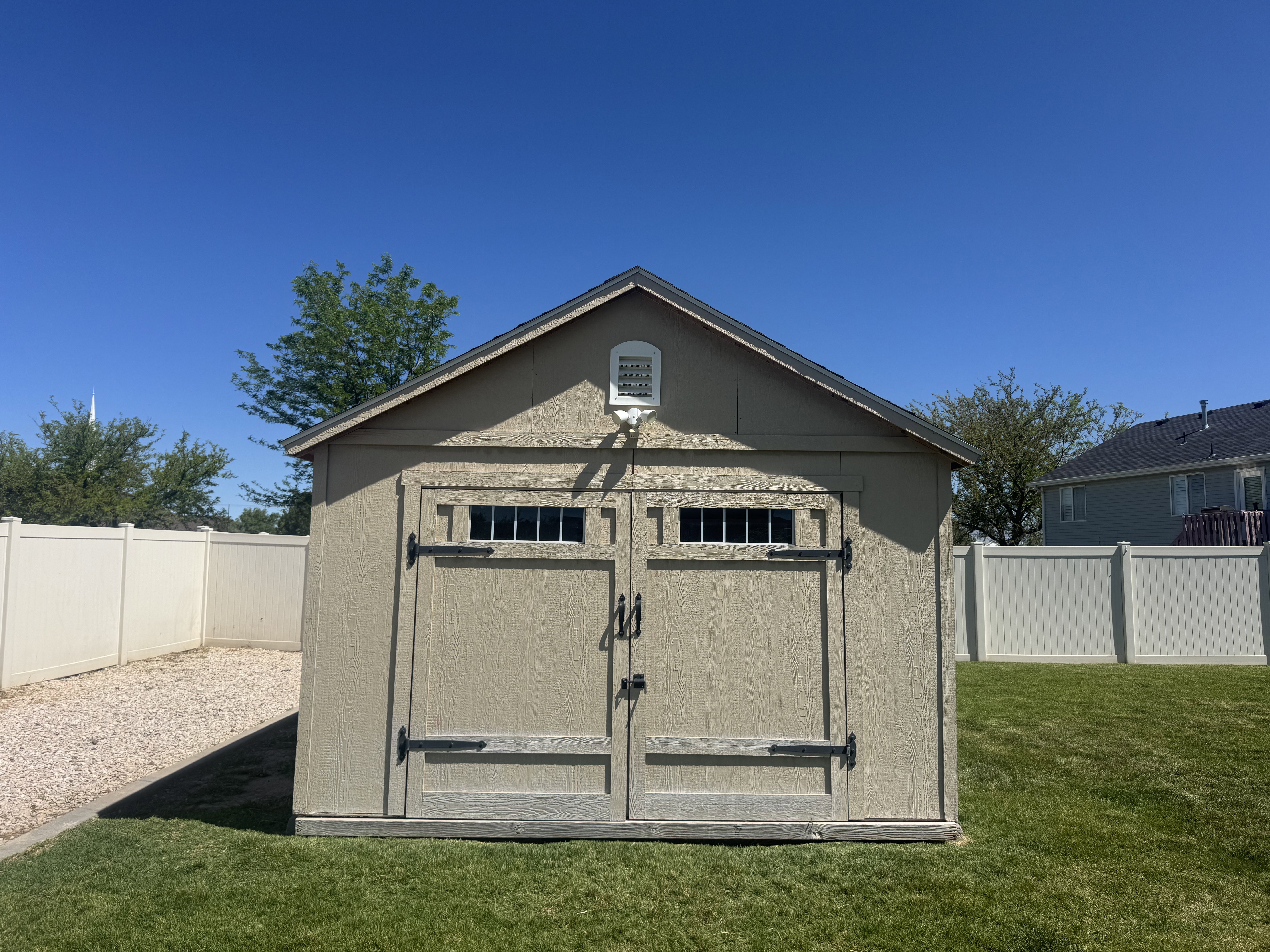 Gable-roof storage shed featuring dual double doors with upper transom windows and black hardware