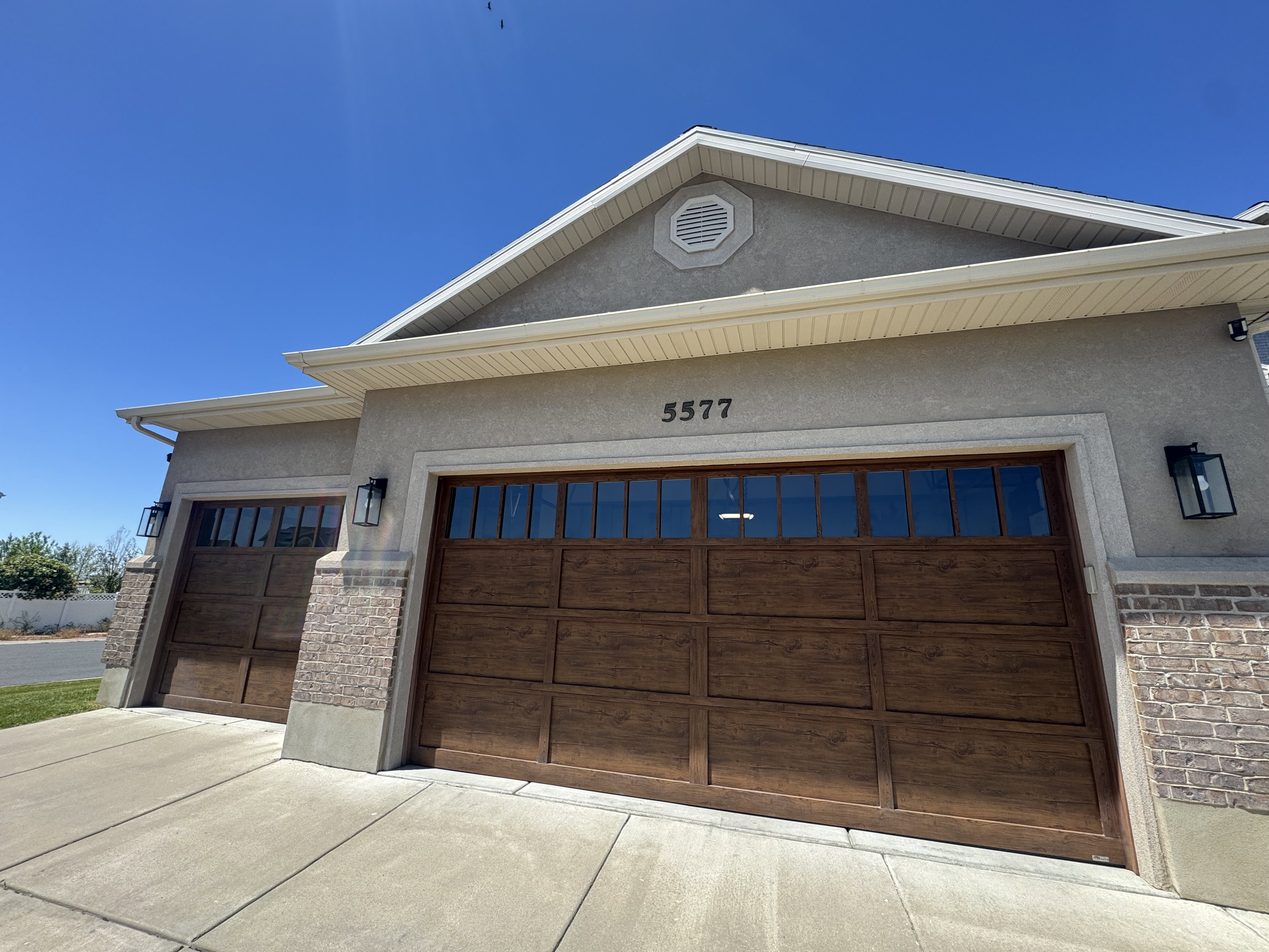 Stucco exterior featuring two wood-finish garage doors with upper window panels