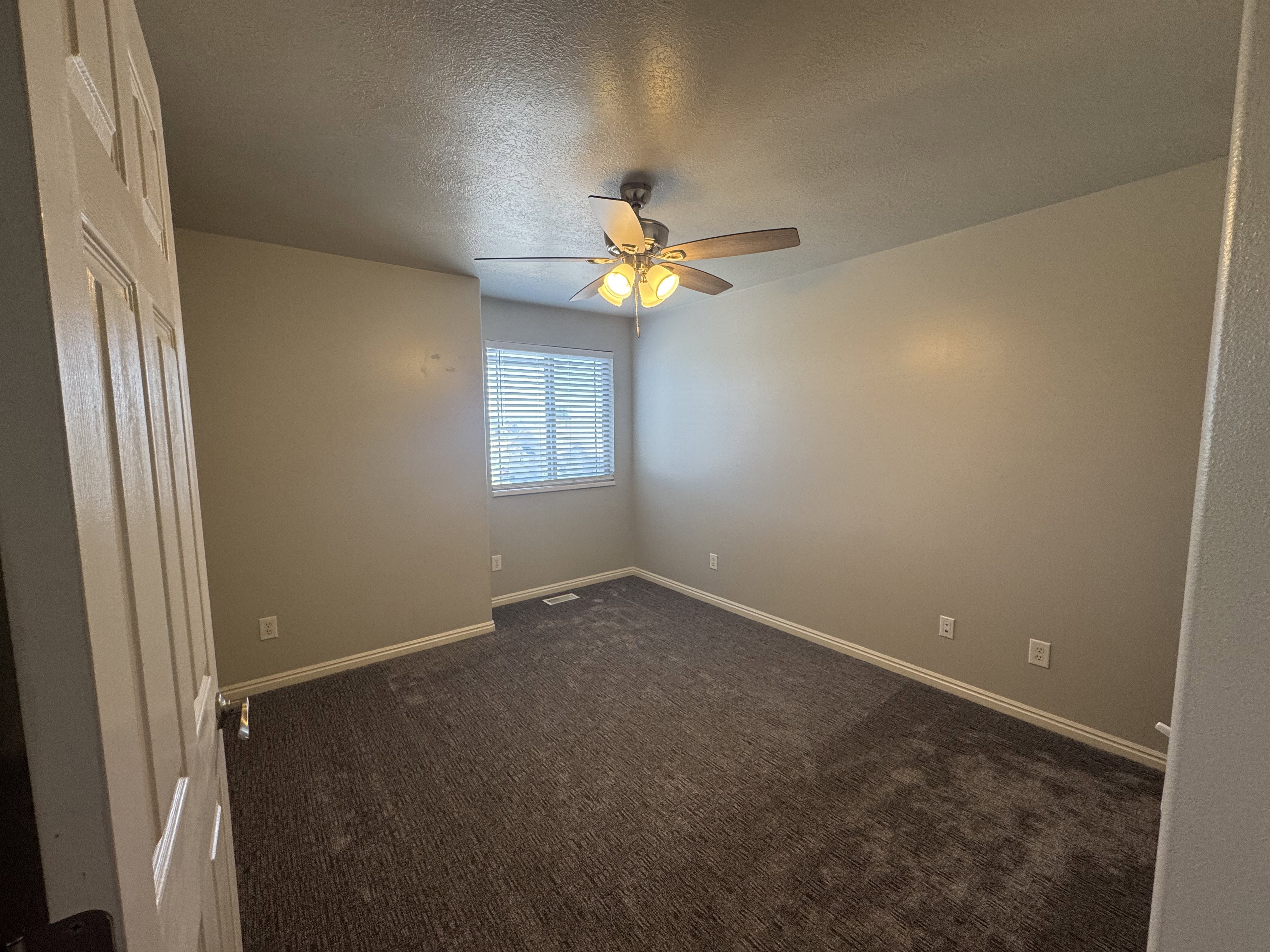 Carpeted room with a window featuring horizontal blinds, a ceiling fan with integrated lighting, and neutral wall tones