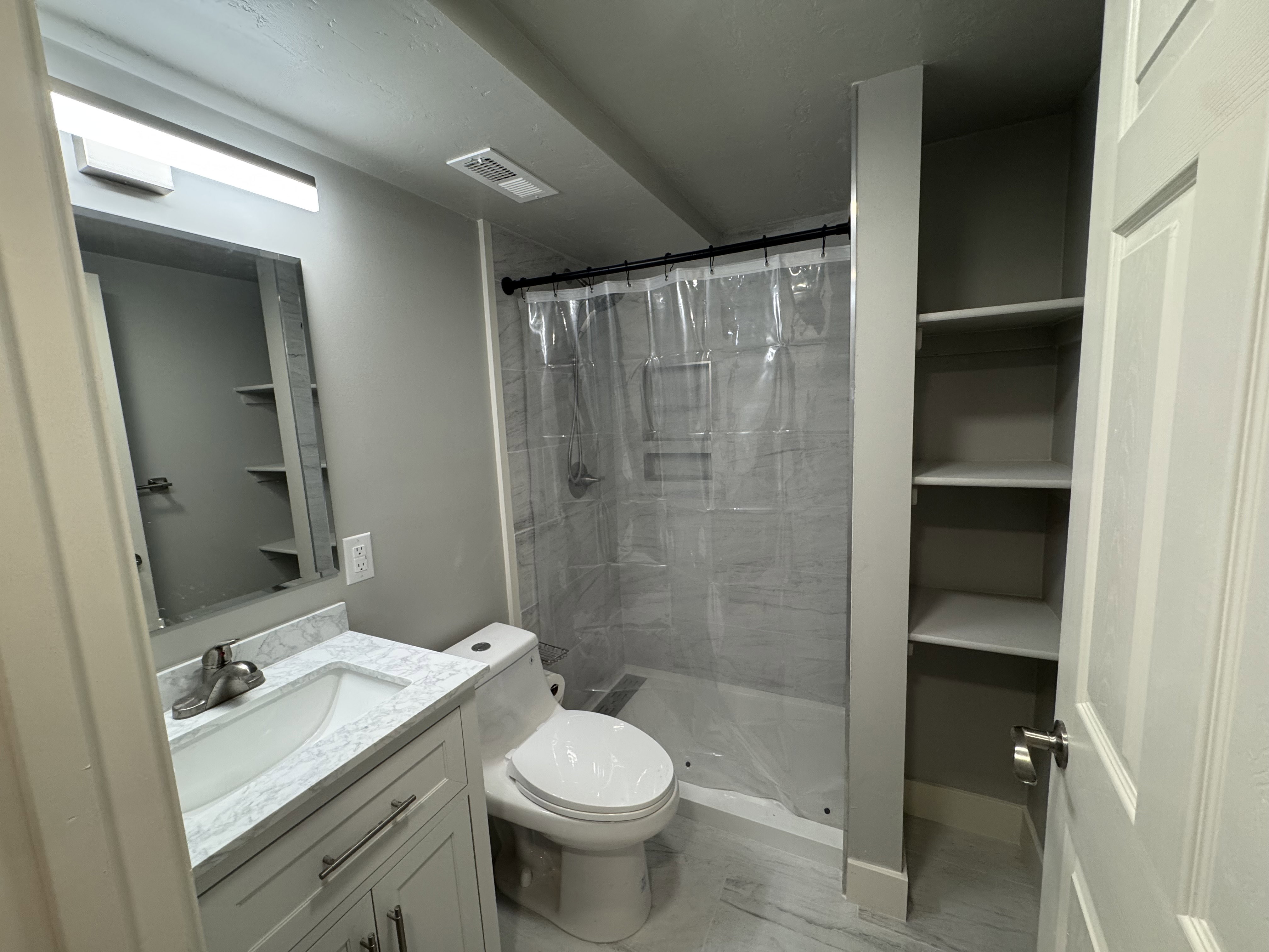 Bathroom featuring a vanity with a white marble-finish countertop, undermount sink, and chrome faucet