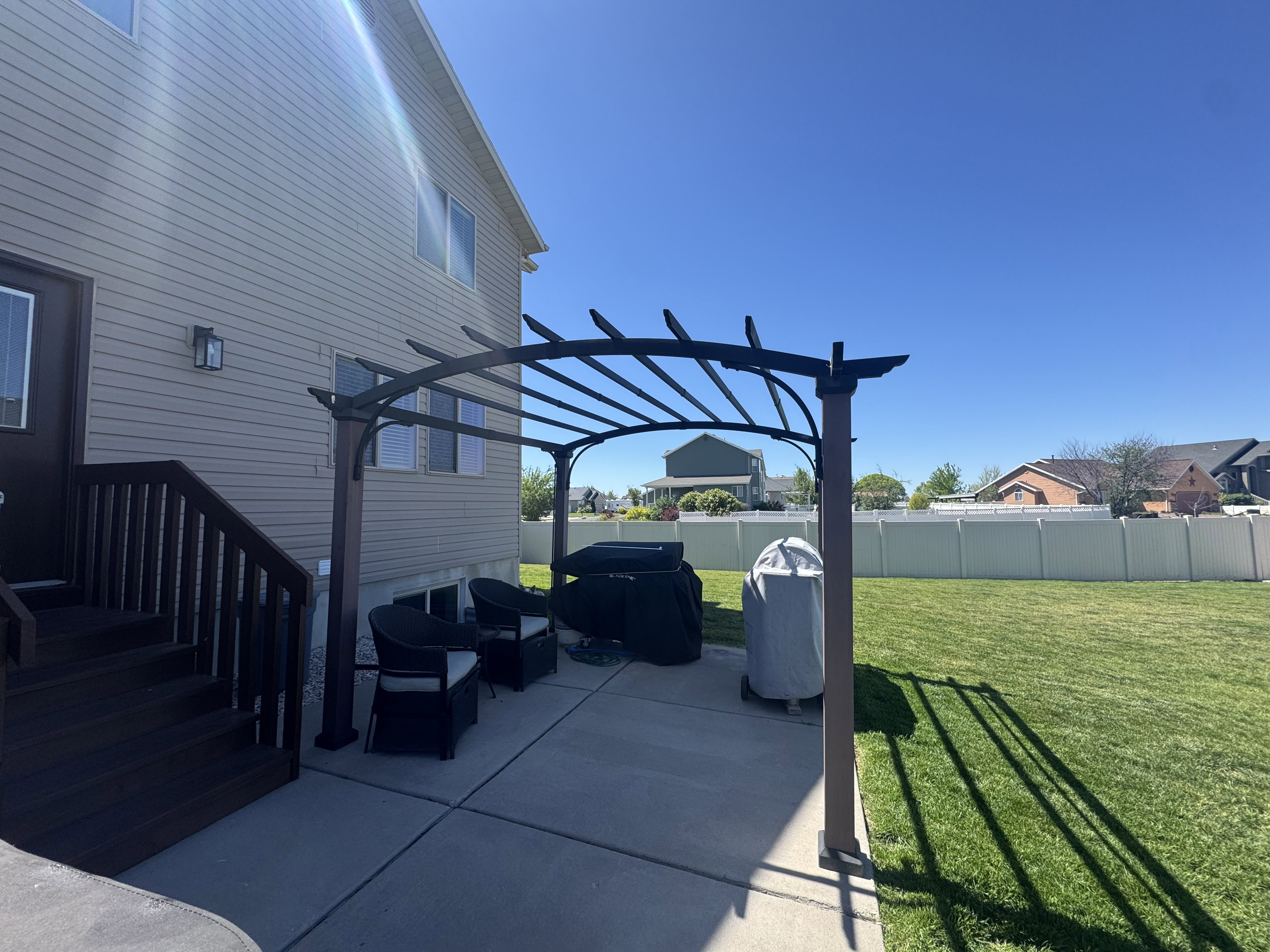 Expansive backyard featuring a pergola-covered patio, manicured lawn, and privacy fencing
