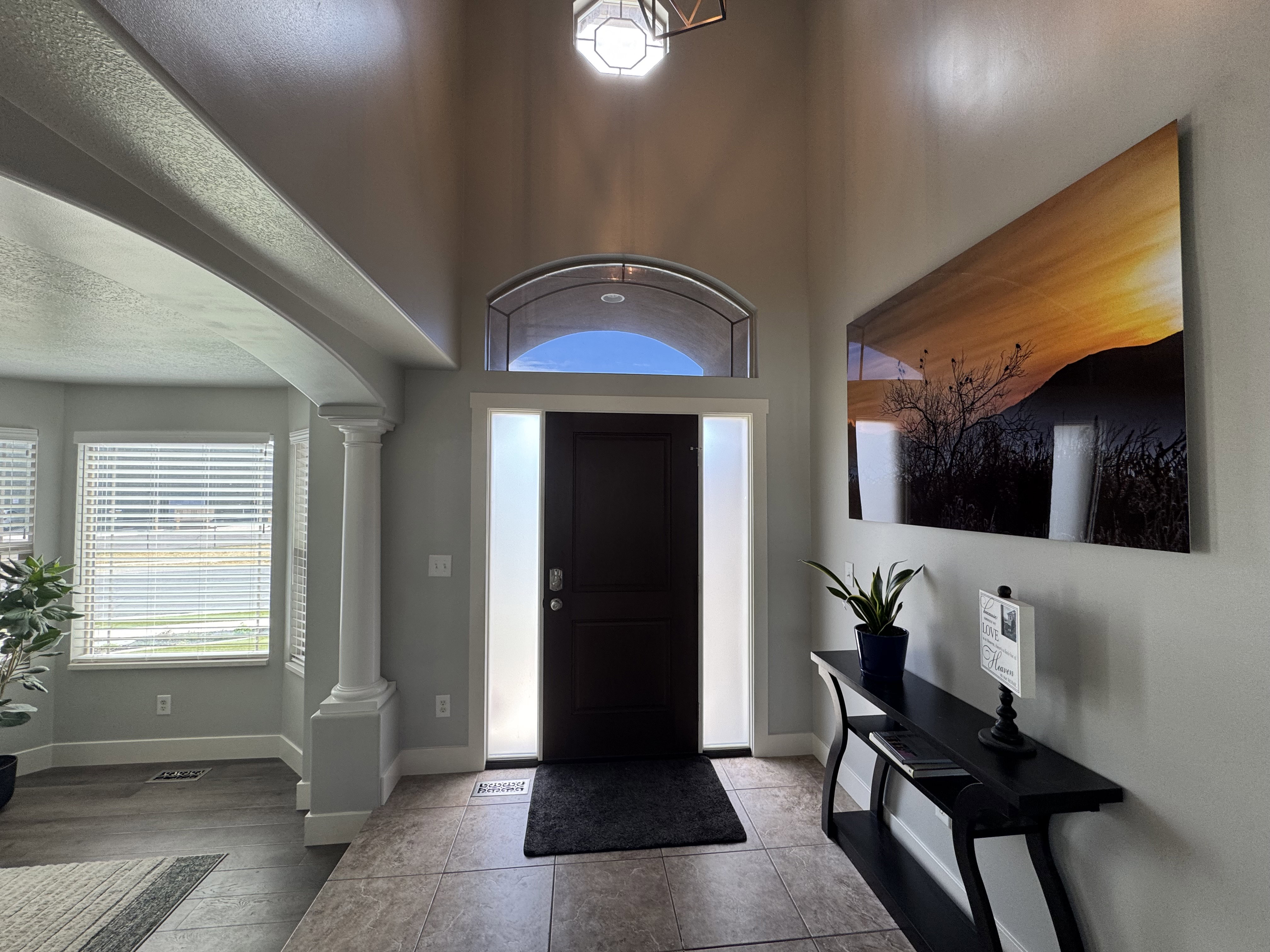 Entryway featuring a dark paneled door with frosted sidelights and an arched transom window