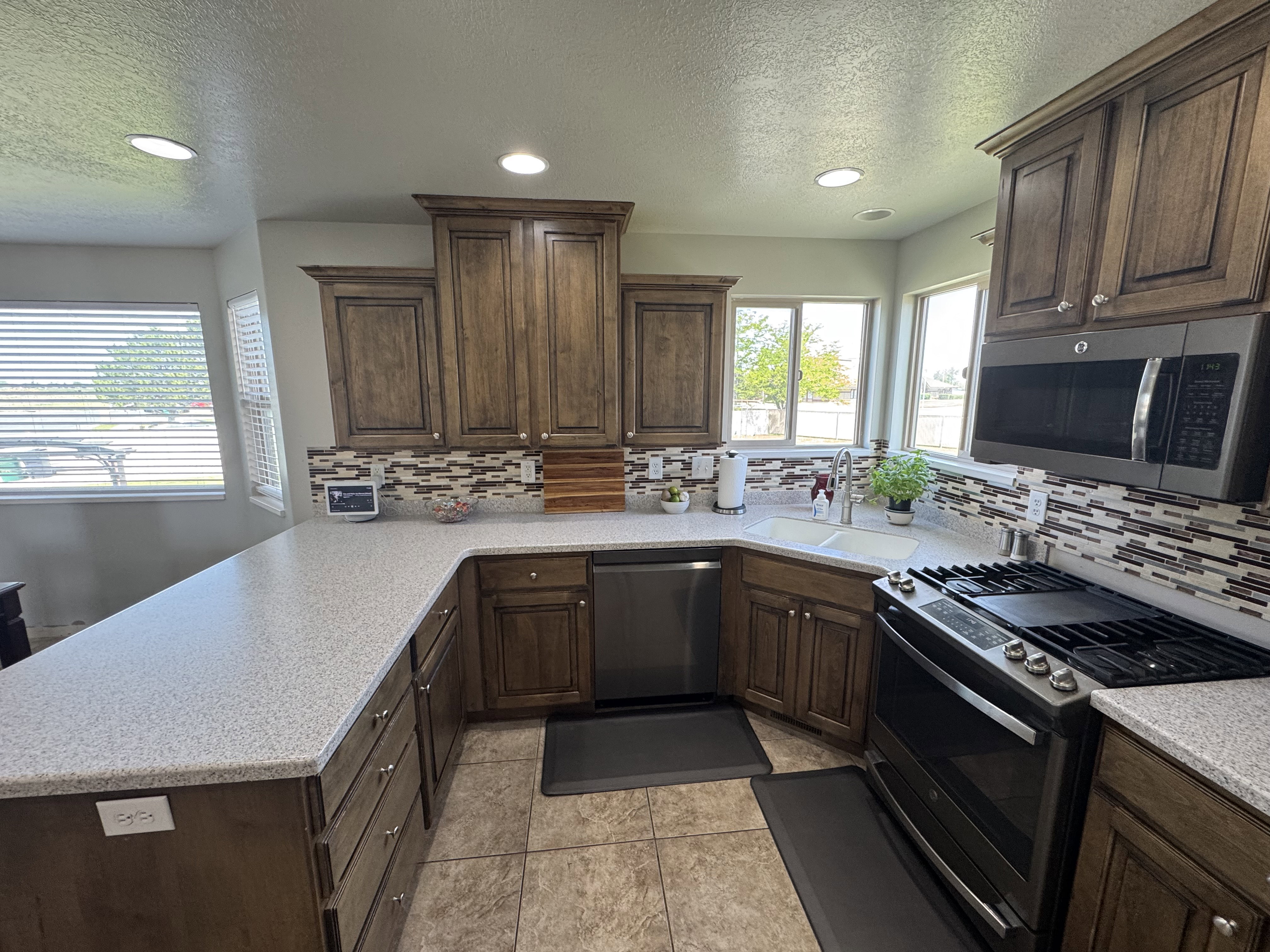 Kitchen featuring wood cabinetry, light-colored speckled countertops, and a mosaic tile backsplash