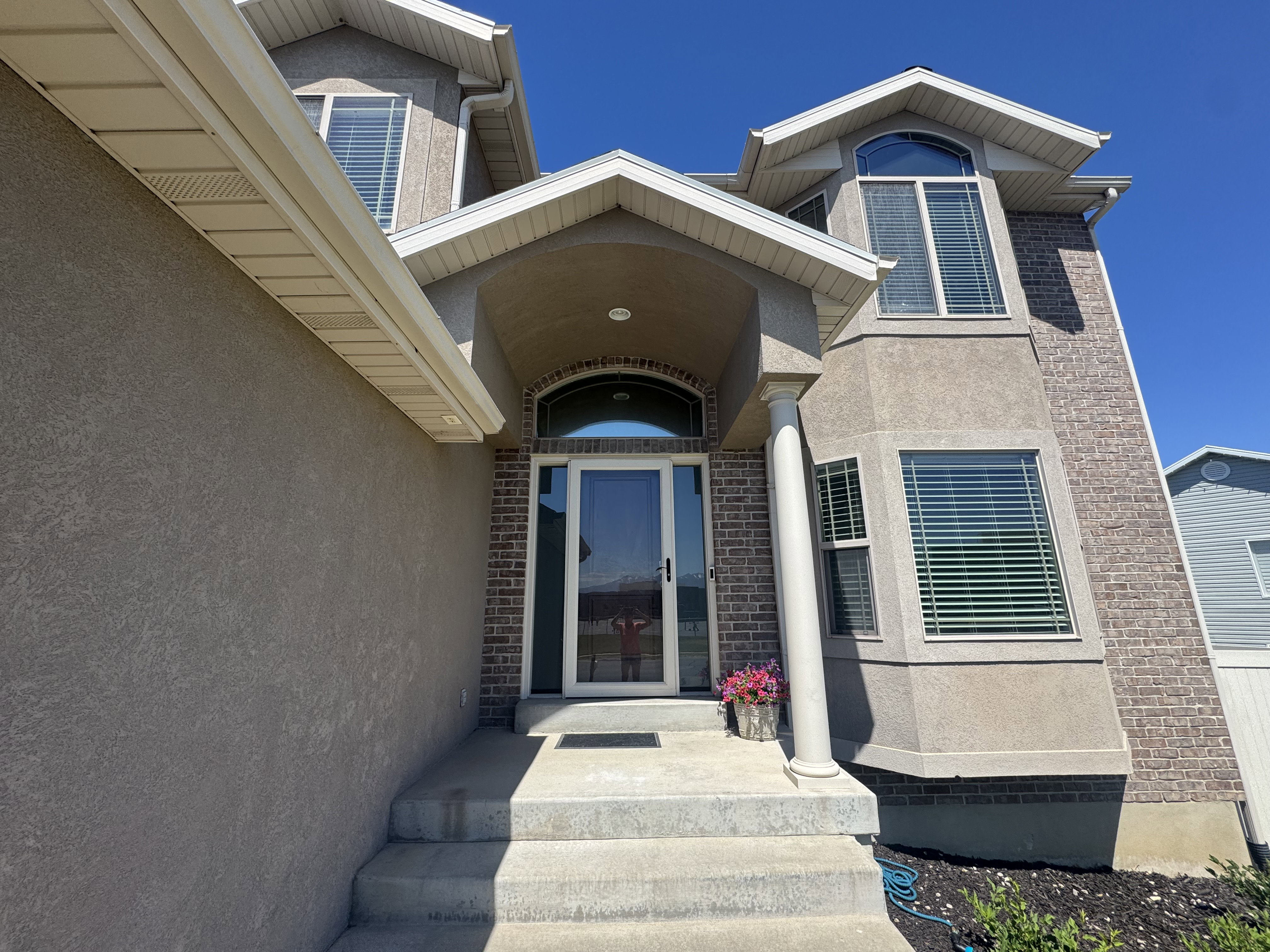Inviting entry with a covered porch featuring a white column, an arched transom window, and a full-light door