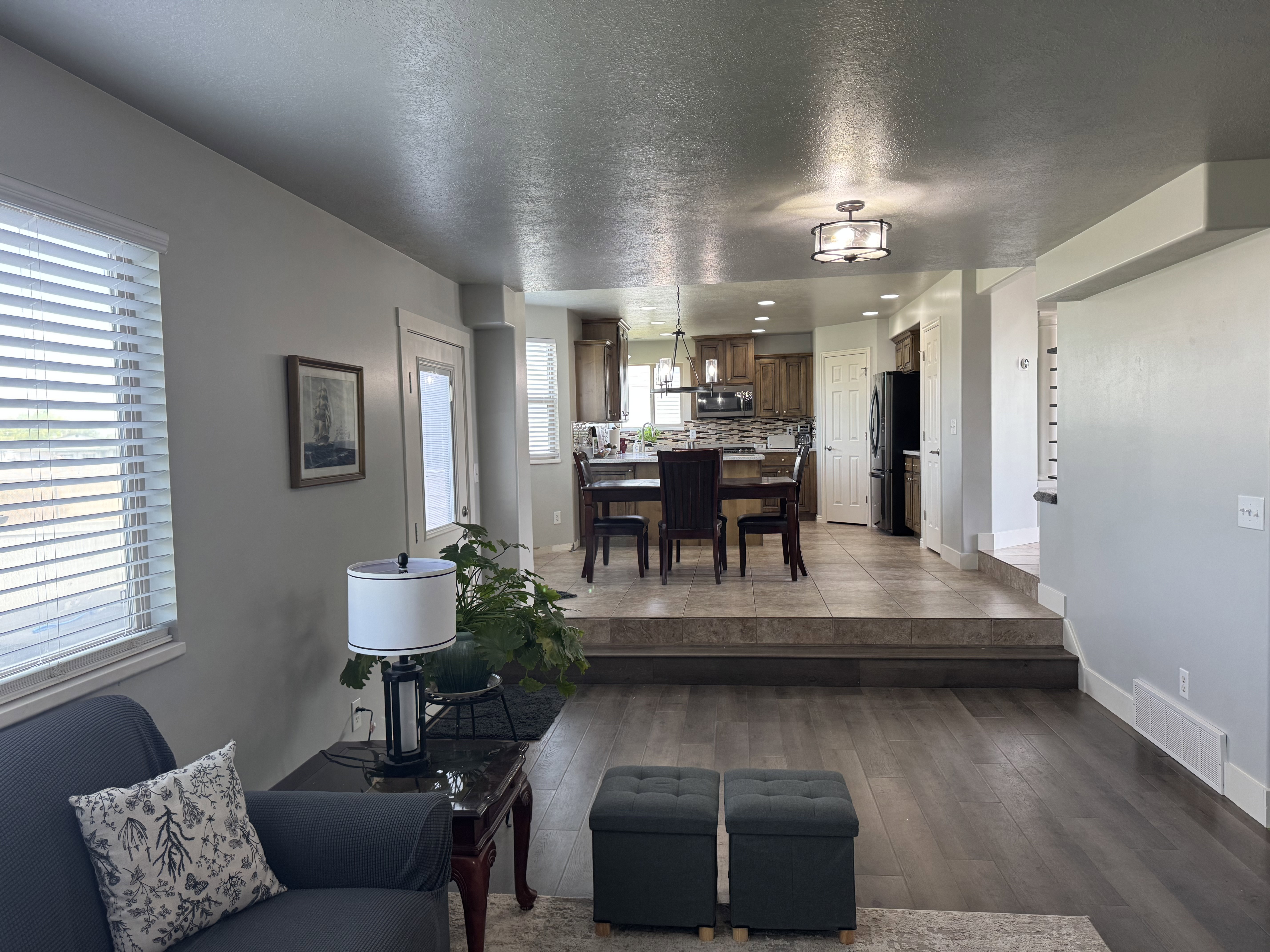 Open-concept living area with wood-finish flooring transitioning to a tiled kitchen and dining space
