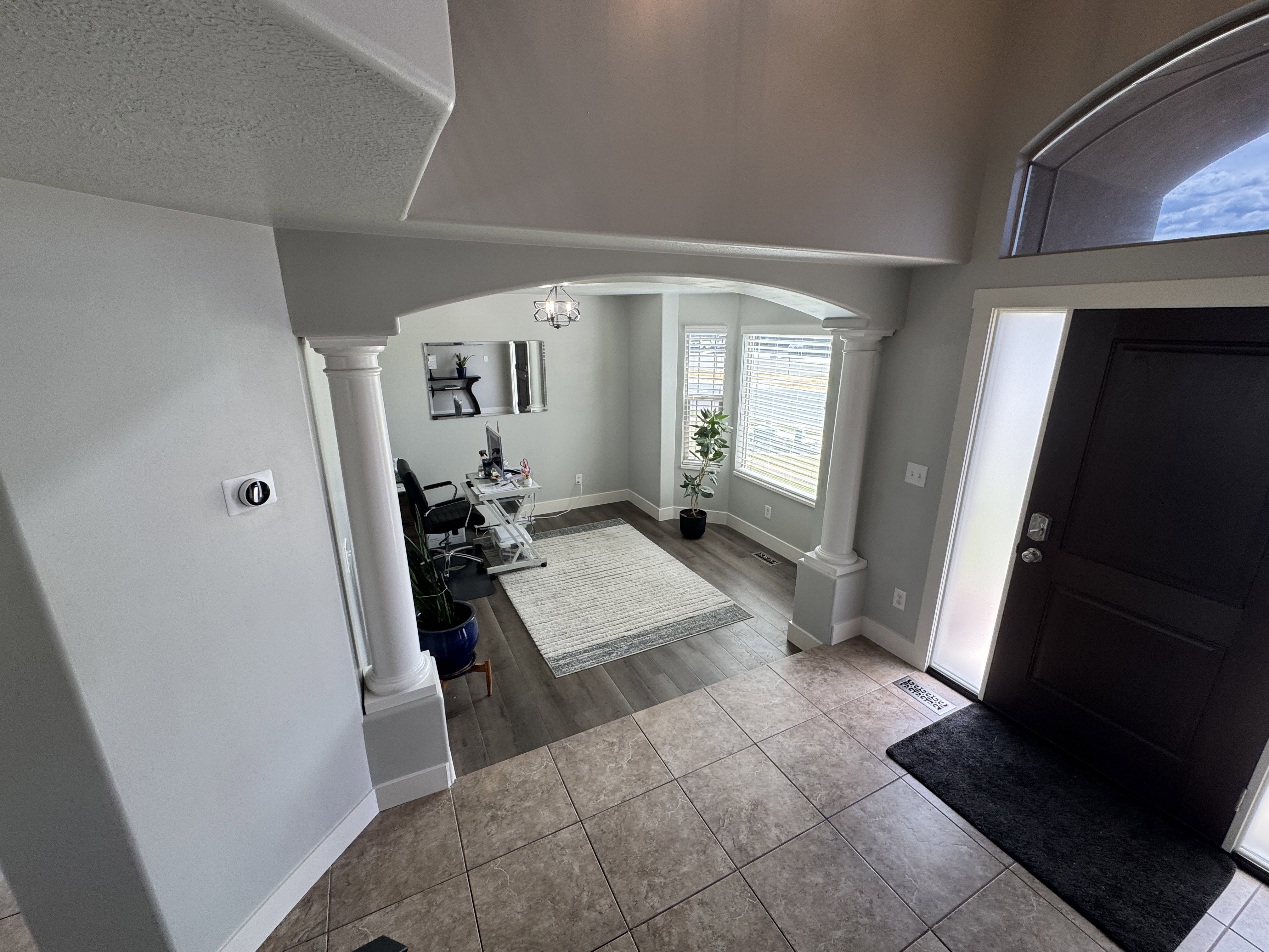 Entryway featuring ceramic tile flooring, a dark paneled door with frosted sidelight, and an arched transom window