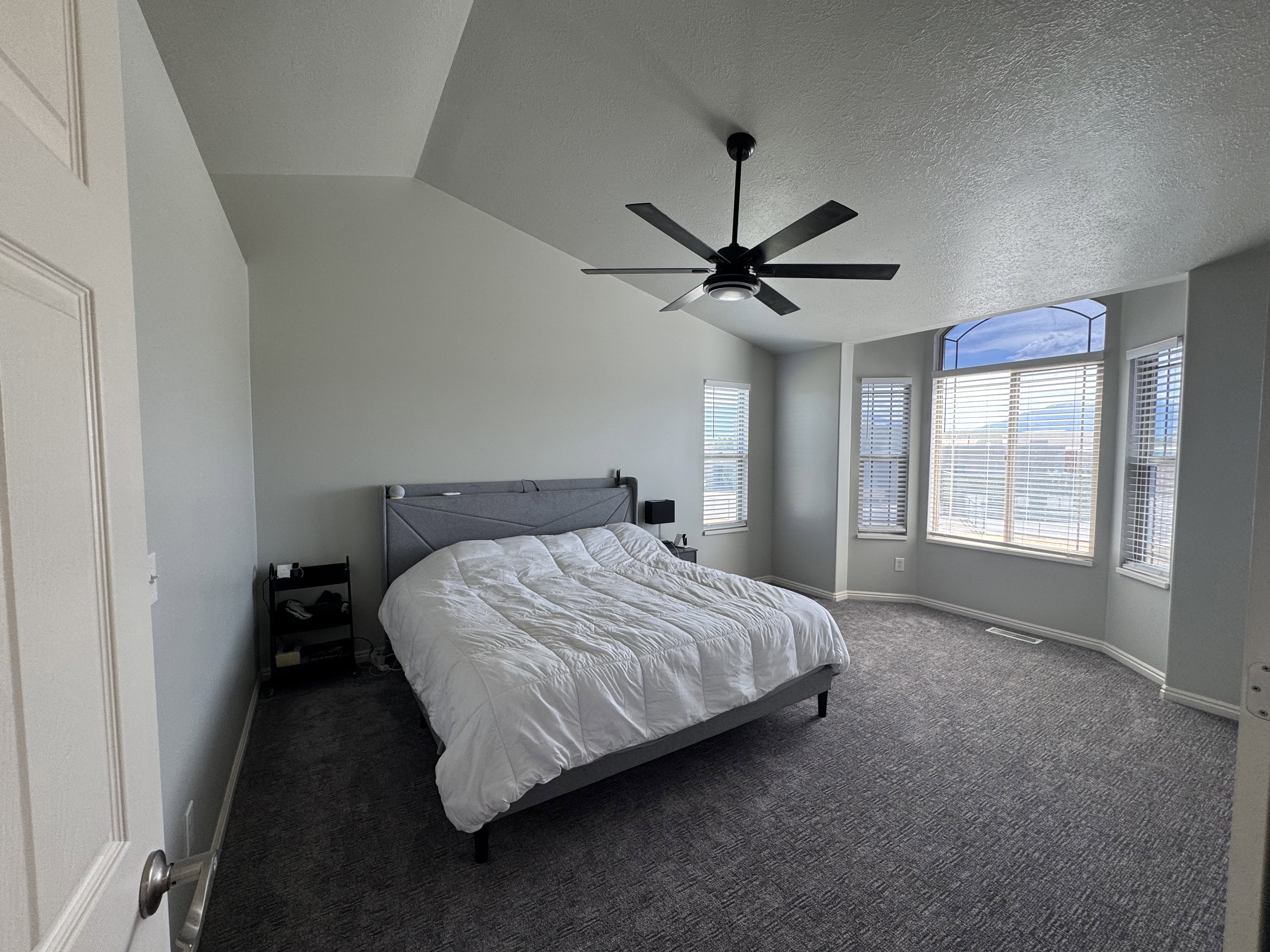 Room featuring a vaulted ceiling and a modern black ceiling fan