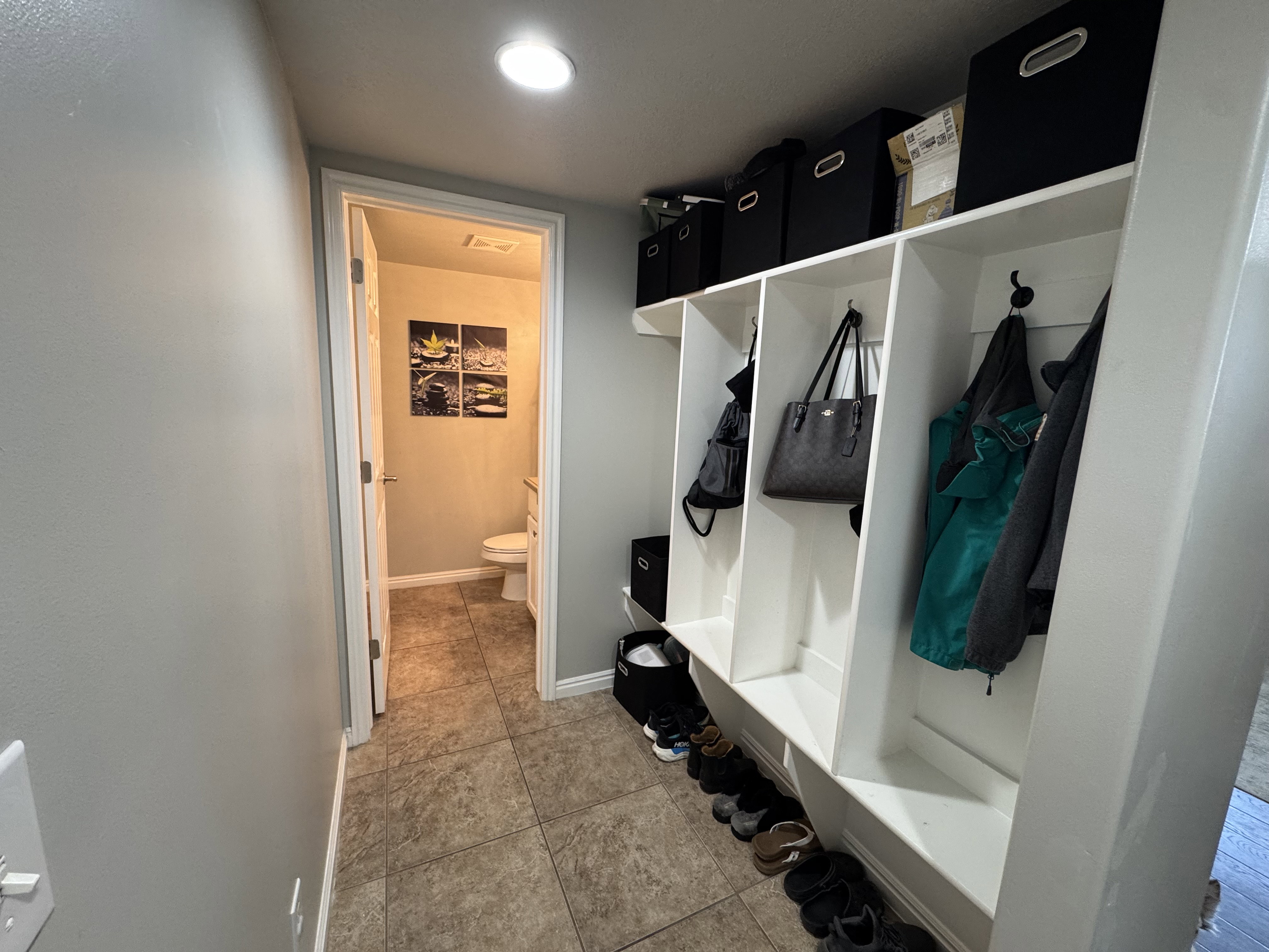 Built-in white storage cubbies with hooks and overhead shelving