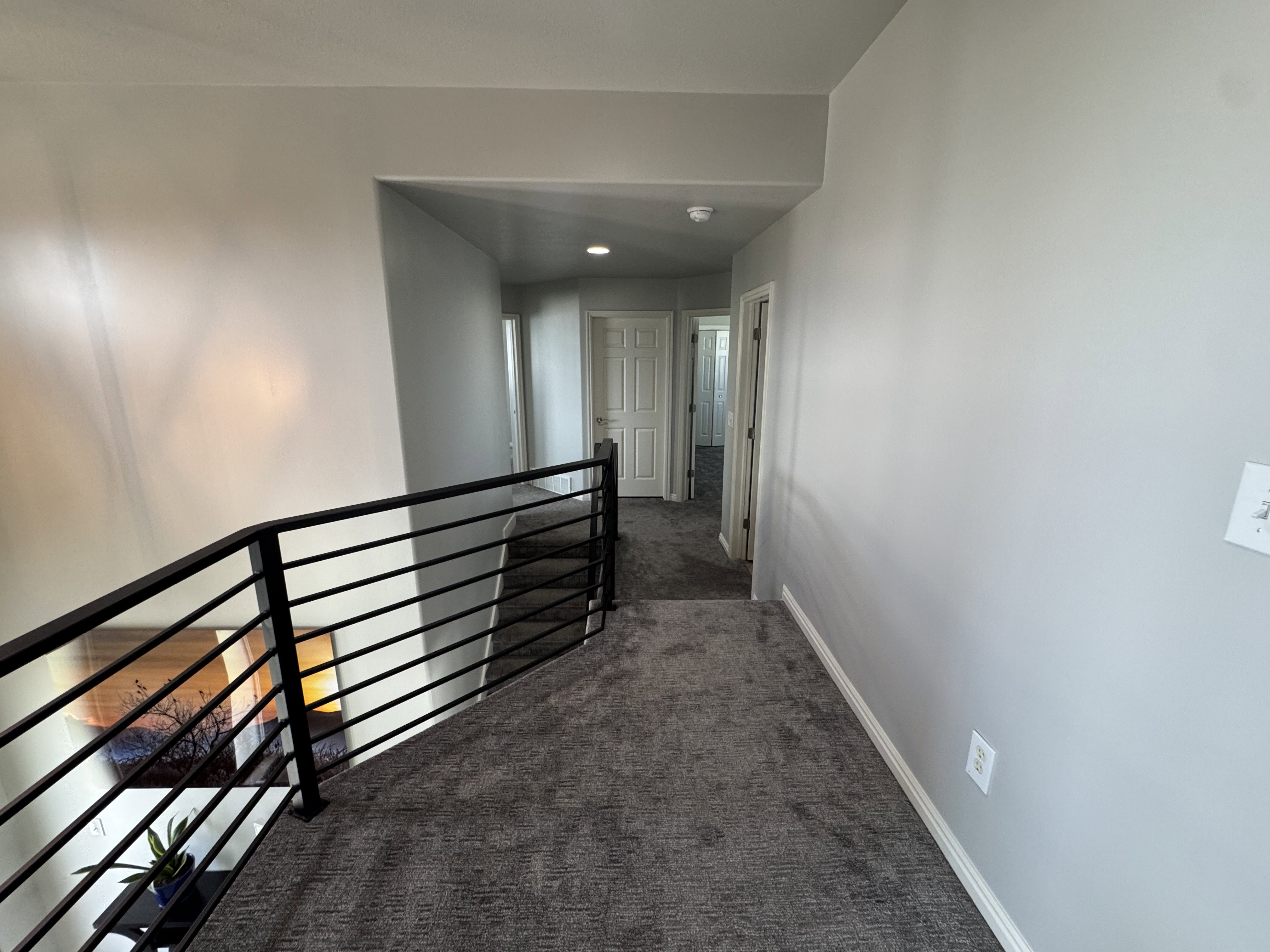 Upper-level hallway featuring textured grey carpeting and light grey wall paint