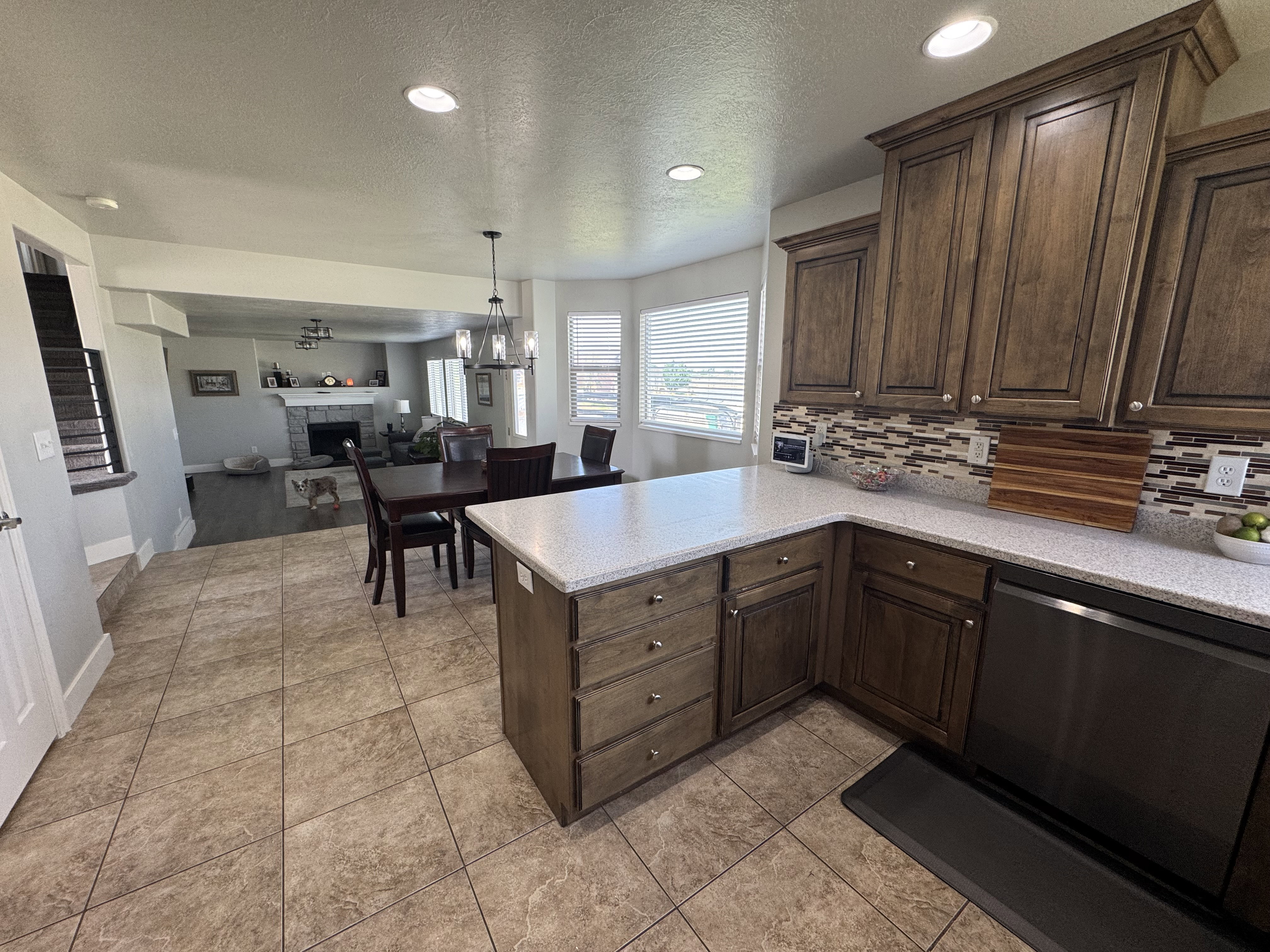 Kitchen featuring wood cabinetry, light-toned countertops, a mosaic tile backsplash, and a built-in dishwasher