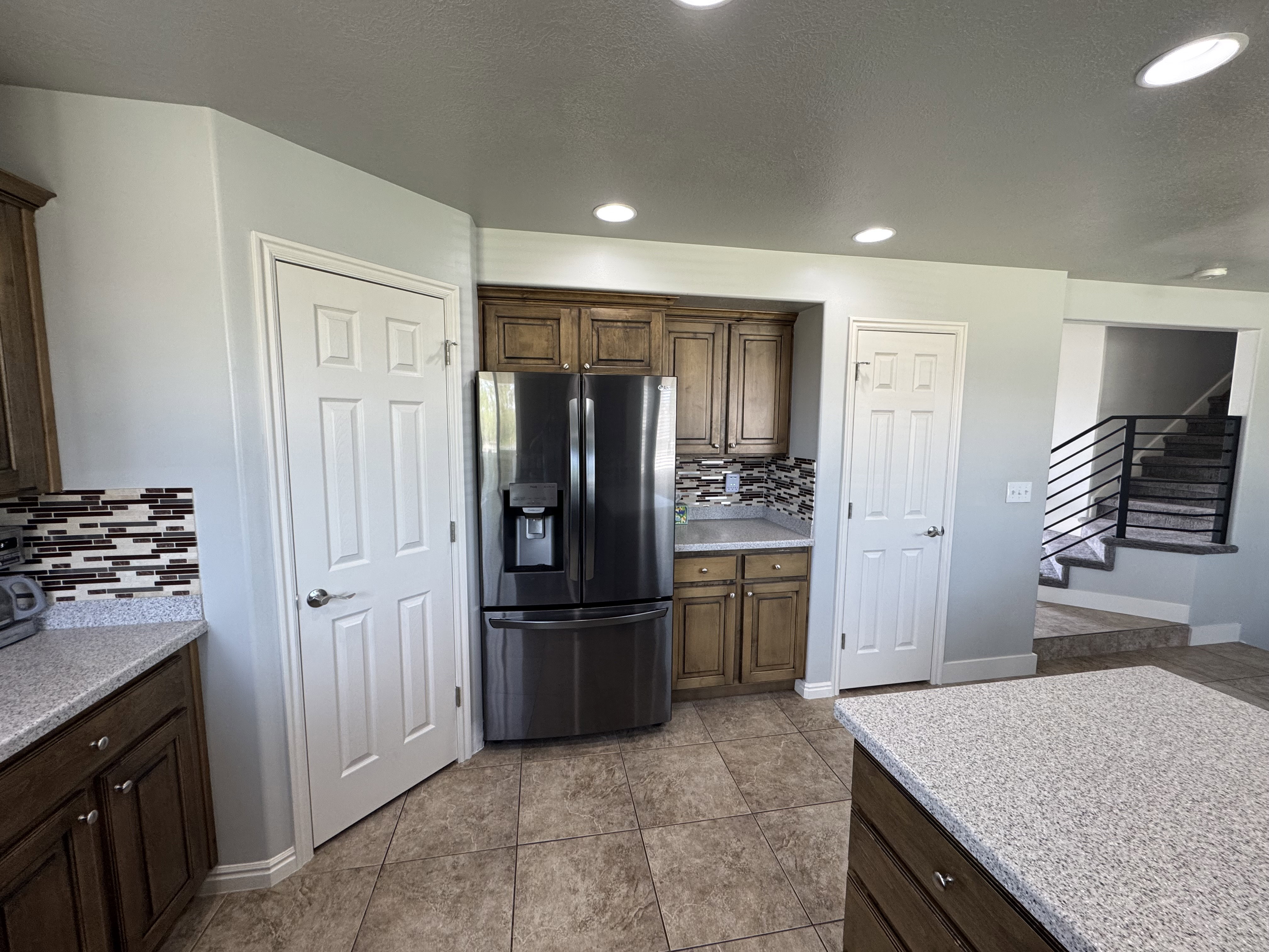 Kitchen area with warm-toned wood cabinetry and a tile backsplash