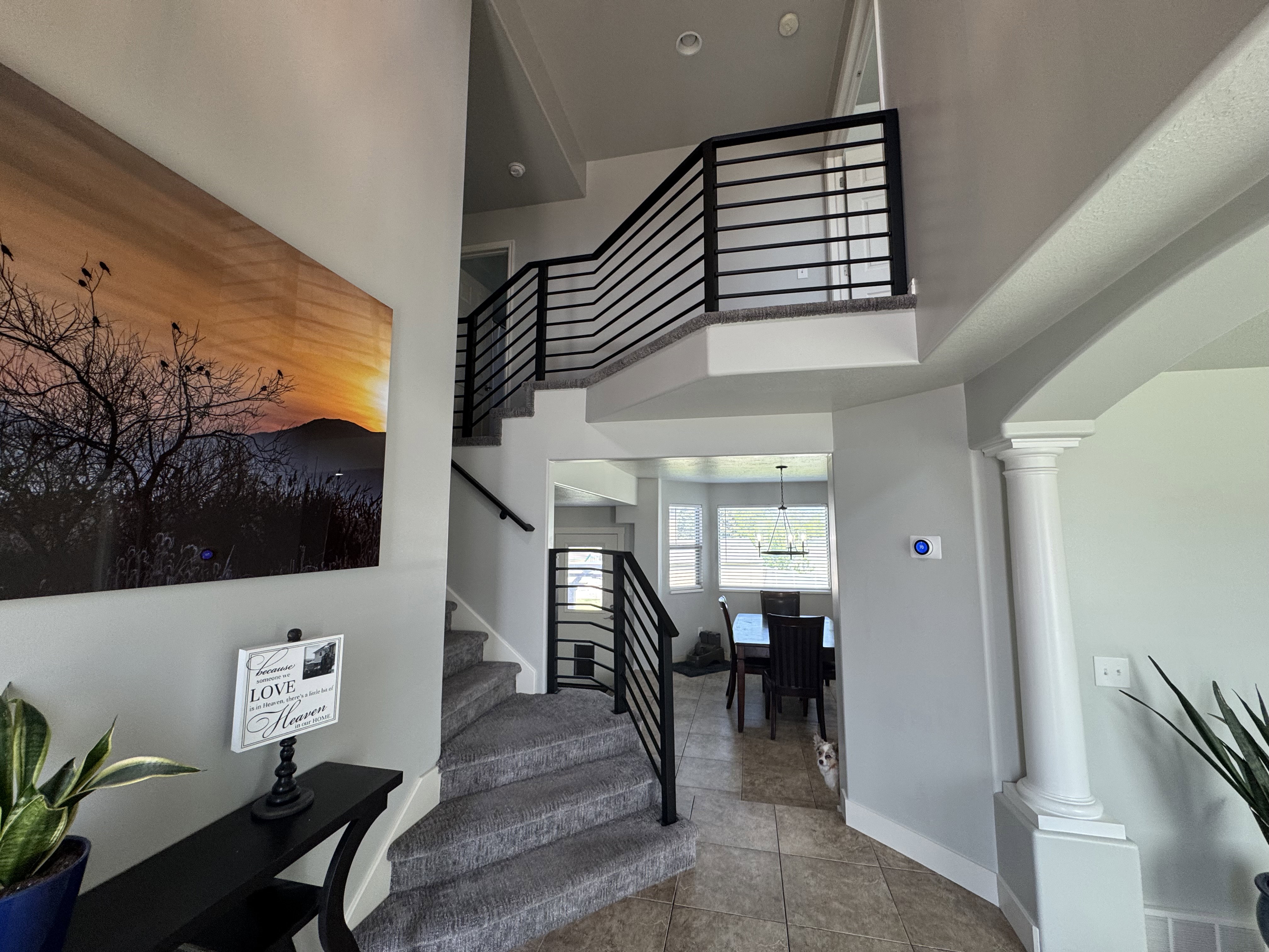 Grand foyer featuring a multi-level staircase with contemporary black metal railings, neutral toned carpeting, and tile flooring