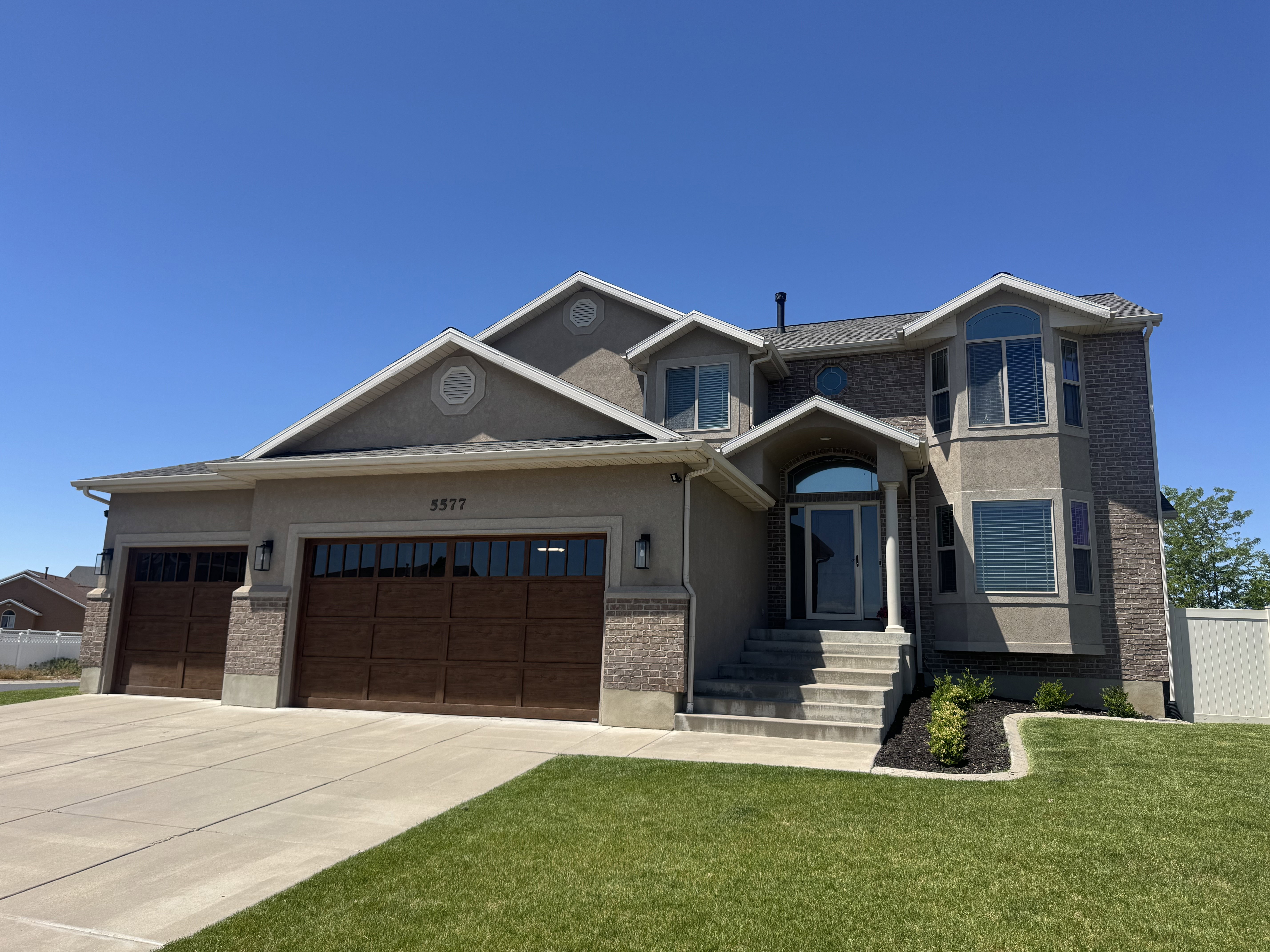 Contemporary two-story residence featuring a combination facade of brick and stucco, an arched entryway with a transom window, and a grand staircase leading to the front door
