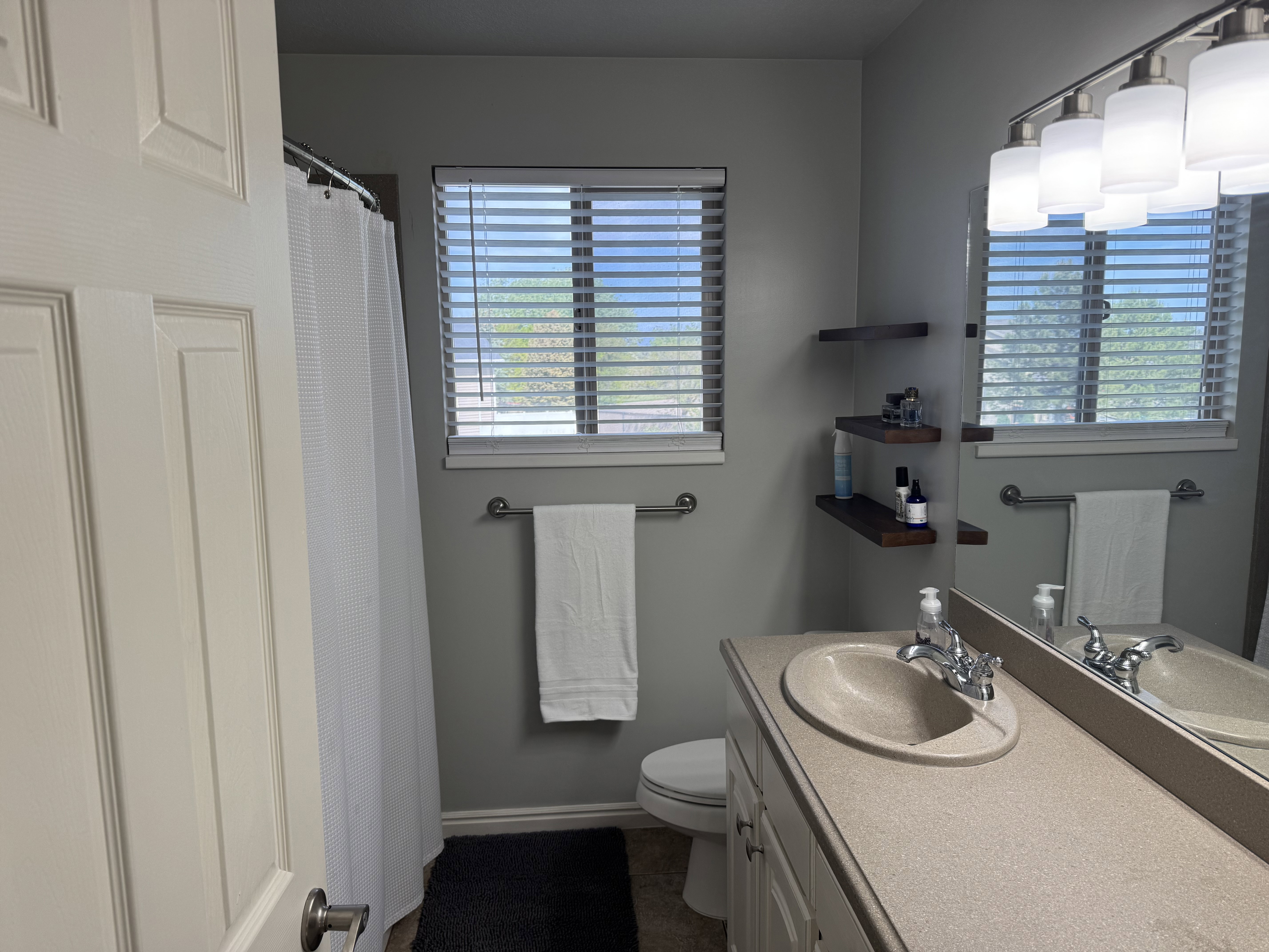 Bathroom featuring a vanity with an integrated sink, a large mirror, and a multi-bulb light fixture