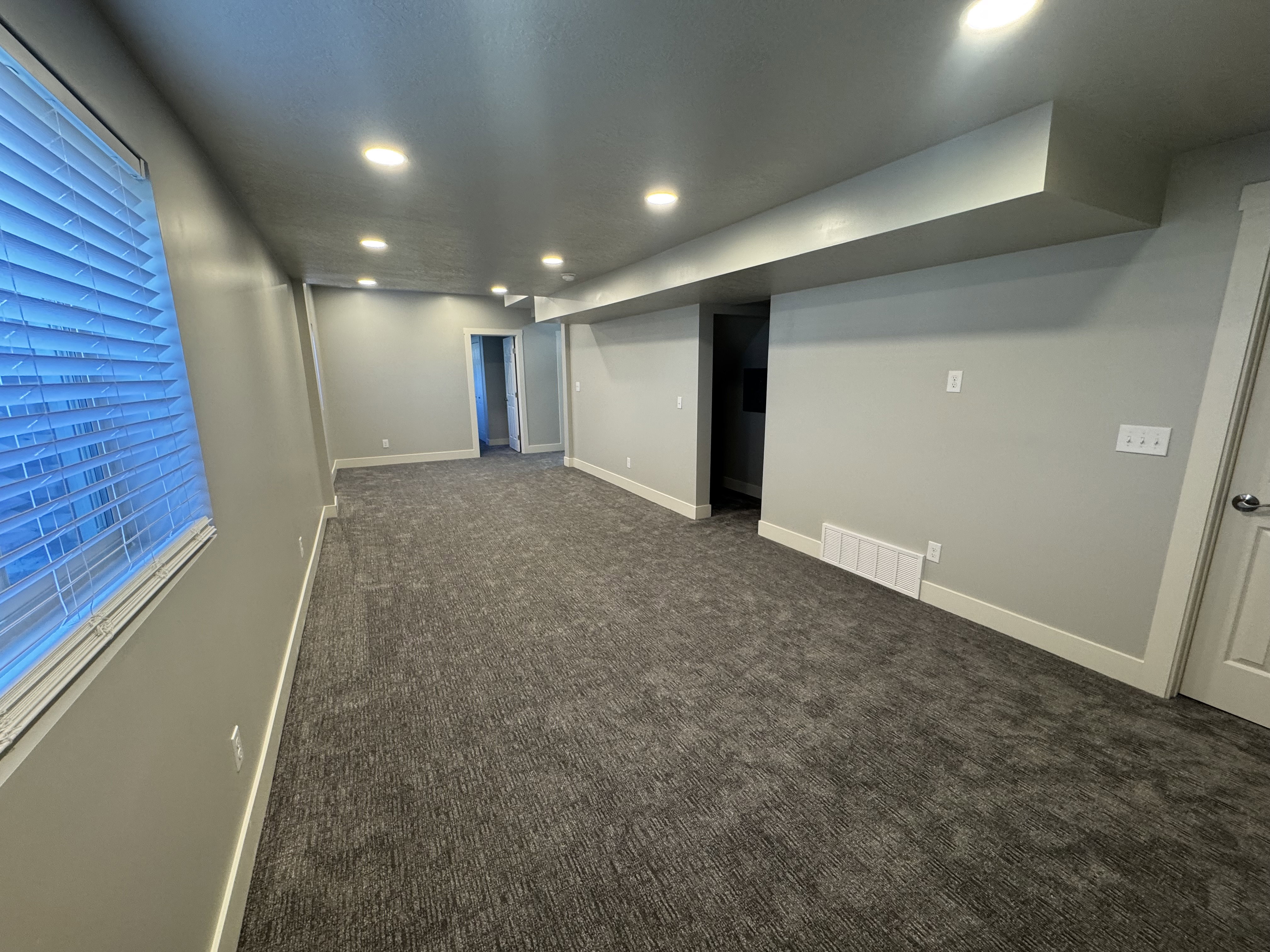 Spacious room with recessed lighting, light gray walls, and textured gray carpeting