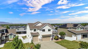 Contemporary two-story residence featuring a white siding exterior, stone accents, two-car garage, and a fenced yard