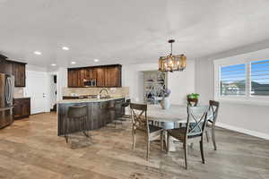 Open-concept kitchen and dining area featuring wood-finish flooring, recessed lighting, and a contemporary chandelier