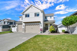 White two-story residence featuring a two-car garage with carriage-style doors, stone accents, and a covered front entry