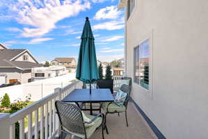 Outdoor balcony with white railing, textured stucco exterior, and a single window with white trim