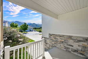 Covered front porch featuring a white spindle railing and a stone veneer accent wall