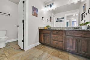 Extended vanity with a speckled countertop, integrated sinks, and ample wood-finish cabinetry