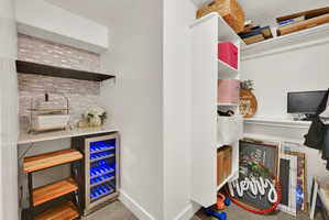 Built-in beverage cooler with blue LED lighting, marble-look countertop, and tile backsplash